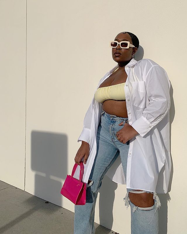 How to Style an Oversized Shirt: Aniyah wears a white shirt with a yellow bra top, ripped jeans, and a pink handbag