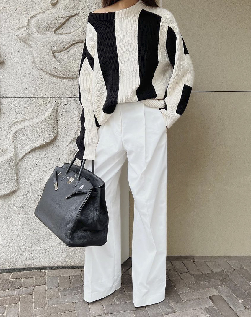 @modedamour wears a black and white vertical stripe knit with white wide-leg jeans