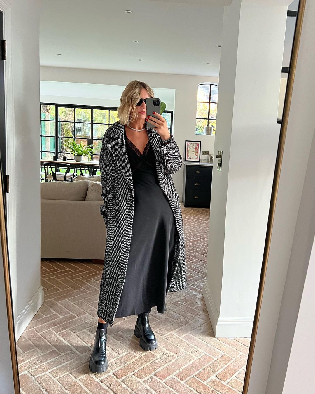 Best boots for women: @emmarosestyle wearing ankle boots with a black dress and long coat