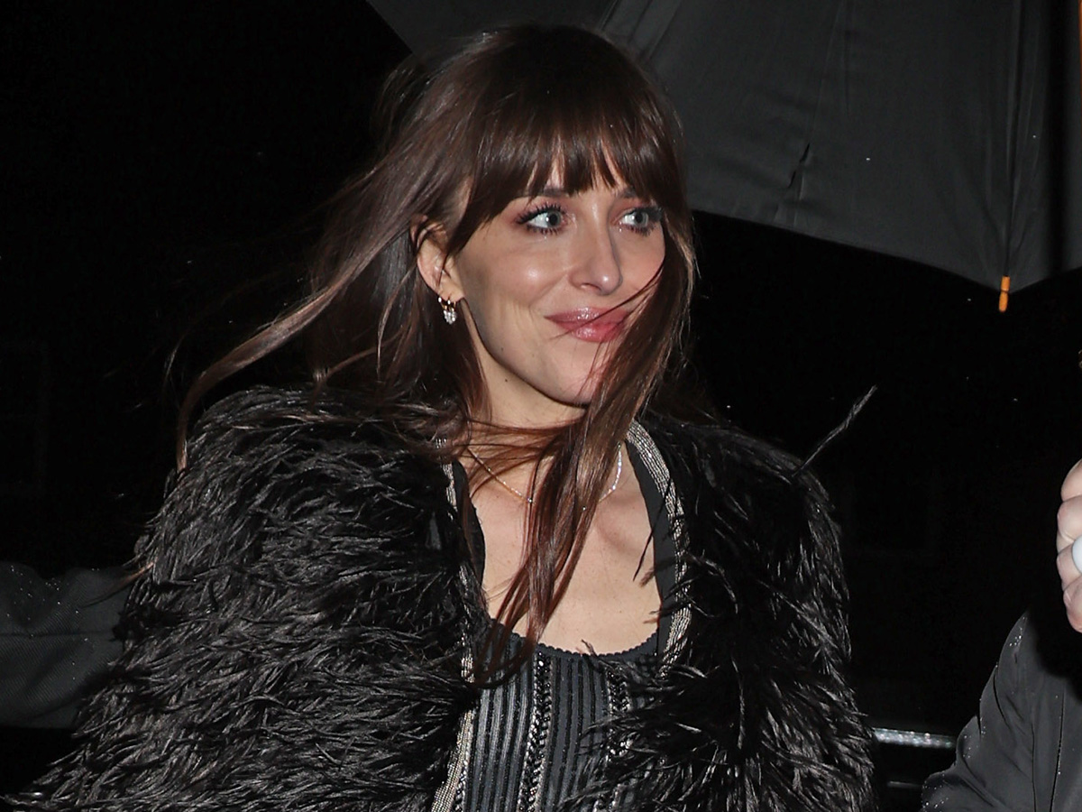 Dakota Johnson wearing a black, sheer gown with a feather shawl at the SNL after party.